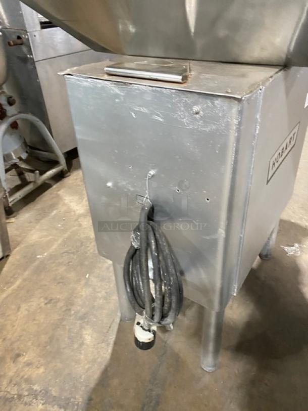 Hobart heavy-duty commercial meat grinder on legs, electric-powered, steel finish, visible power cord, minor surface wear.