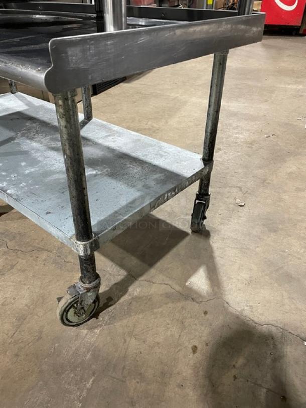 Sapphire stainless steel equipment stand with undershelf, upturned back, side splash, and casters. Used condition.