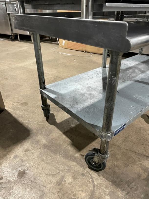 Sapphire stainless steel equipment stand with single undershelf, up-turned back, side splash, and casters. Used condition.