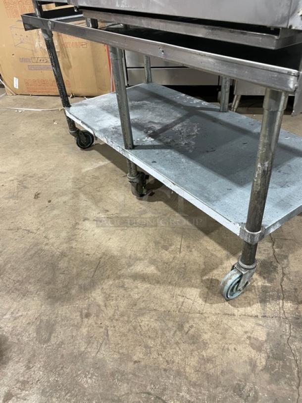 Sapphire stainless steel equipment stand with undershelf, upturned back, side splash, and casters. Used condition.