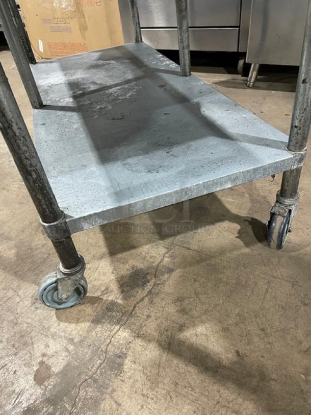 Sapphire stainless steel equipment stand with undershelf, upturned splash, and casters; showing slight wear, suitable for commercial use.