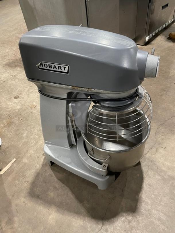 Hobart Legacy HL200-1STD 20 Qt. planetary mixer with stainless steel bowl guard and mixing bowl. Electric, gray, on legs.