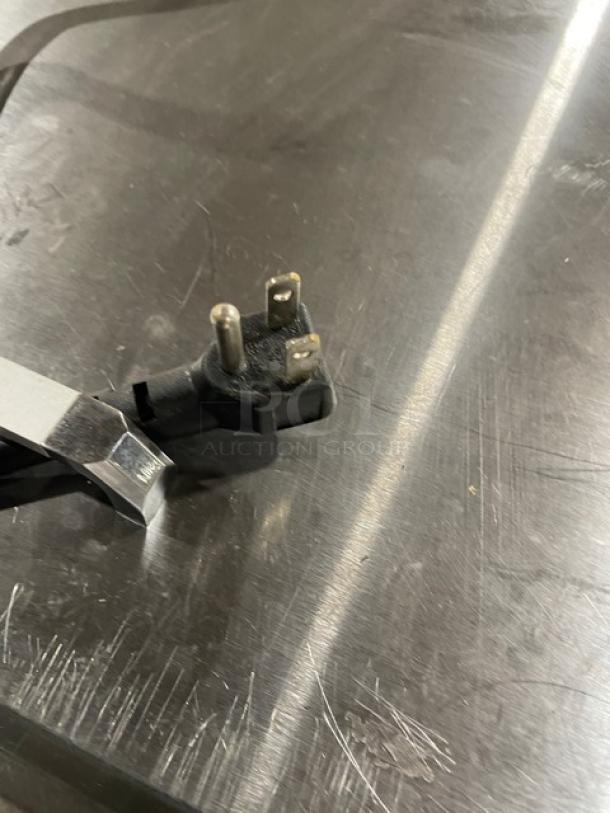 Close-up of a power plug, possibly for an Atosa MSF8305GR refrigerated prep table, on a metallic surface.