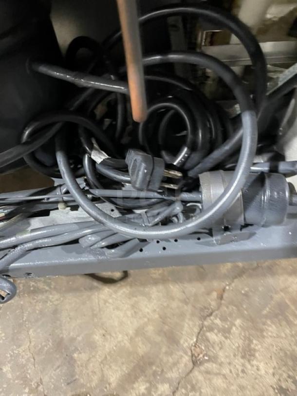 A clutter of black electrical cords tangled on the floor with visible power plugs.