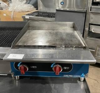 Core Pro Cooking 24" stainless steel flat griddle, model CPG24M. Features back and side splashes, natural gas powered, on legs.