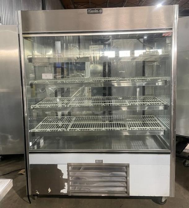 Leader stainless steel refrigerated bakery display case with straight glass, multi-tier shelves, adjustable poly-coated racks, rear sliding glass doors, and casters.