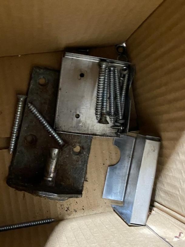 Commercial stainless steel door bracket and screws set in a cardboard box, showing new hardware components.