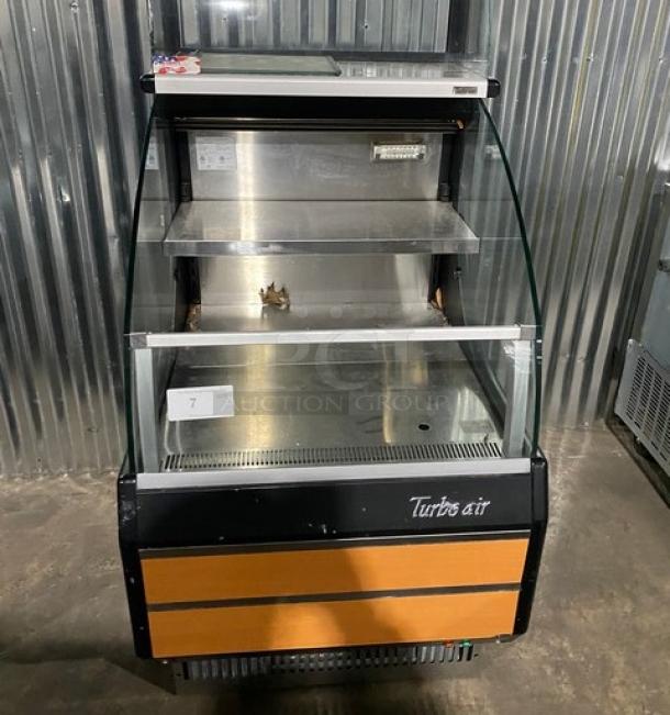Turbo Air TOM-30LB black refrigerated open air merchandiser with stainless steel interior, overhead dry display, dual sliding doors.