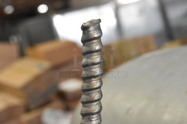 Close-up of the spiral agitator from a Hobart H-600T mixer. The metal shows signs of wear. Background out of focus.
