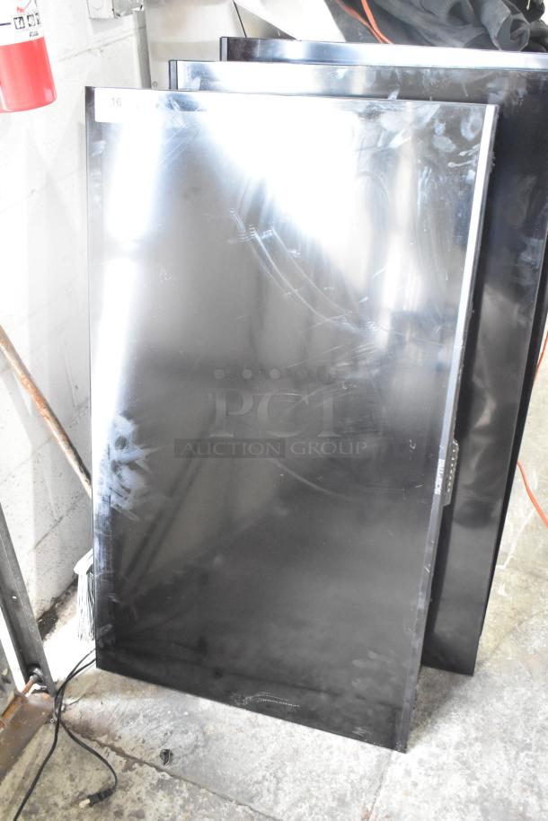 Three flat-screen televisions, including one Sceptre, stacked in a garage. Screens have marks and show wear. Local pickup only.