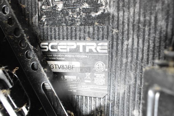 Close-up of a Sceptre TV label showing model GTV83BF, input specifications, and safety certifications. Dust visible on surface.