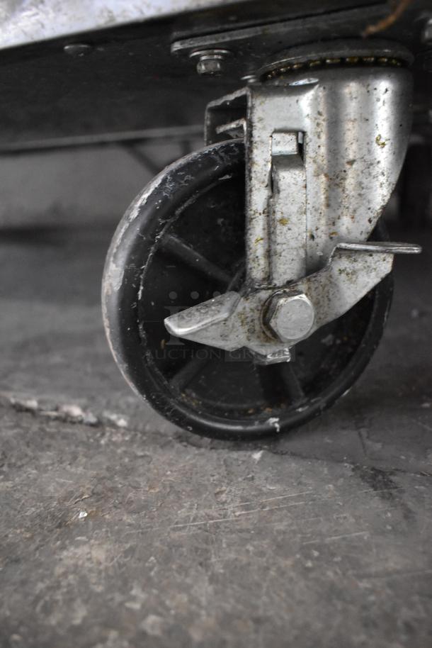 Commercial caster of Dukers DSP48 Sandwich Salad Prep Table, showing slight wear, allows for easy mobility.