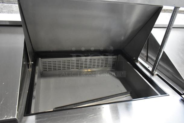 Dukers commercial prep table with open lid, showcasing interior storage. Features 2-tier shelf, on casters, 115V, 1 Phase.