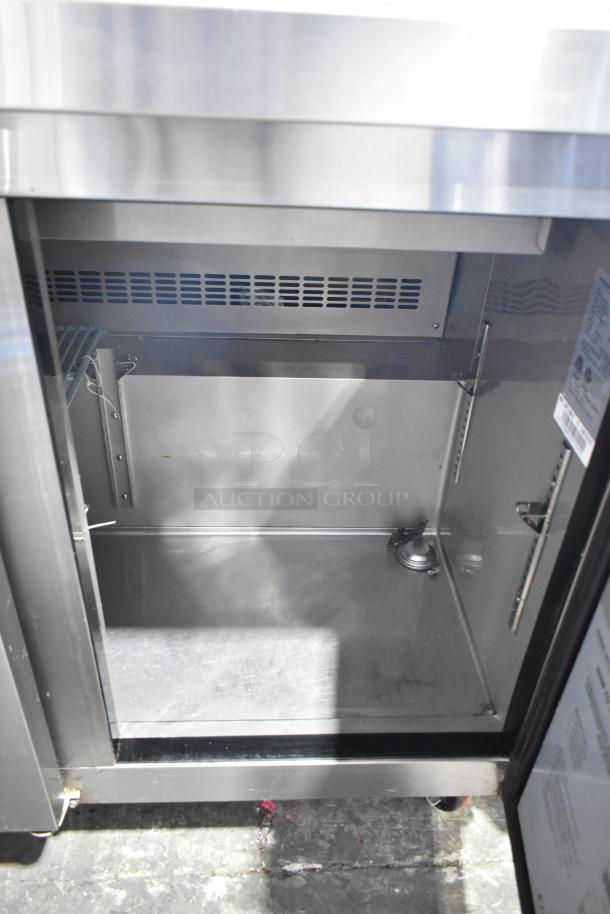 Dukers Commercial Prep Table, stainless steel interior, open door view, clean condition, with visible air vent and shelving mounts.