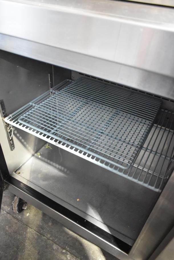 Dukers commercial prep table interior with wire shelf, stainless steel build, on casters, visible over shelf, 115V, 1 phase.