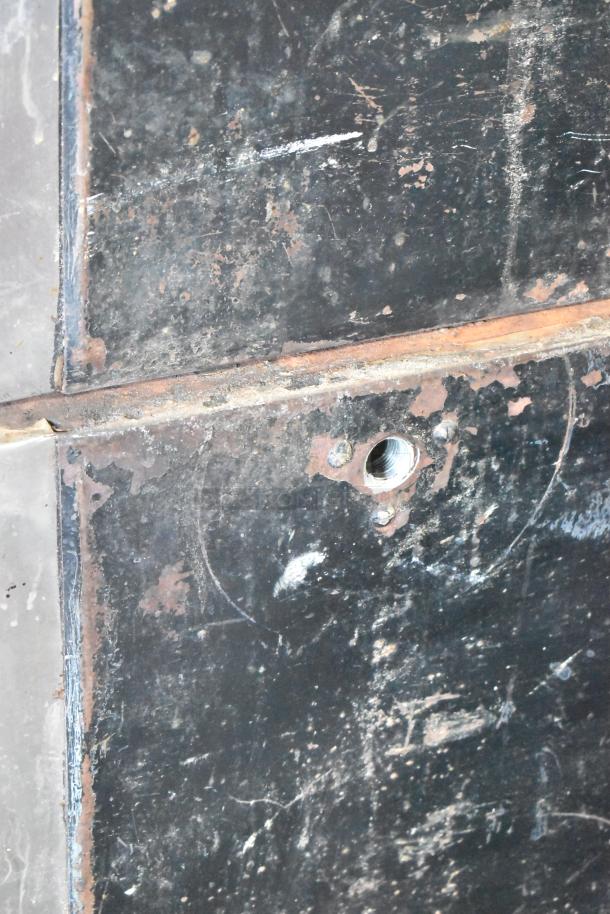 Close-up of the metal surface of a Bari M54S pizza oven, showing signs of wear and rust, with visible bolts and gas inlet.