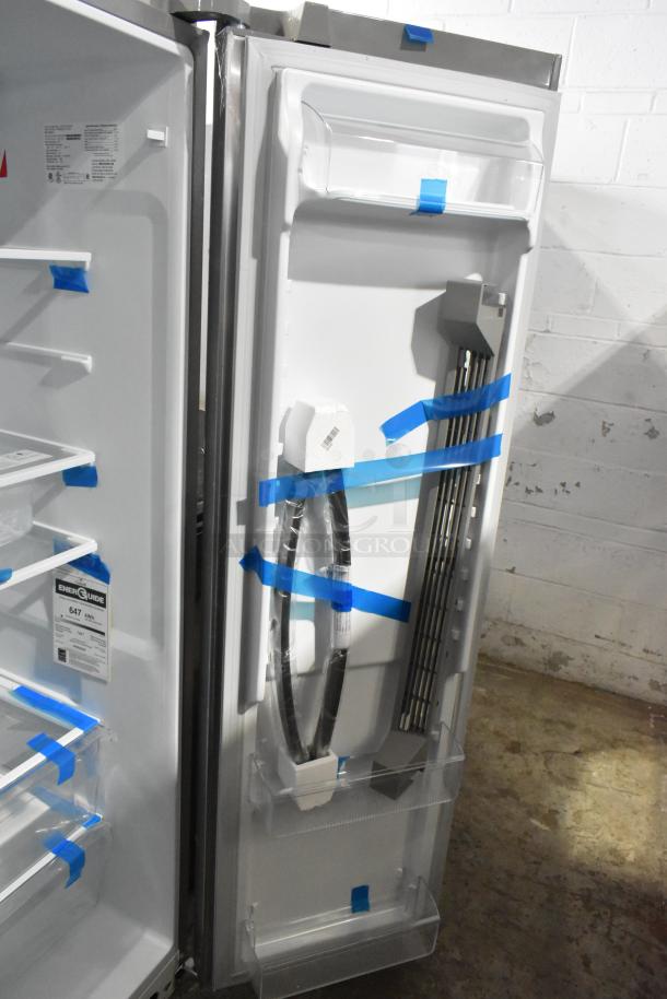 Brand new Frigidaire FRSS2623ASM cooler with freezer, shows slight scratches/dents. Features shelves and energy guide label.