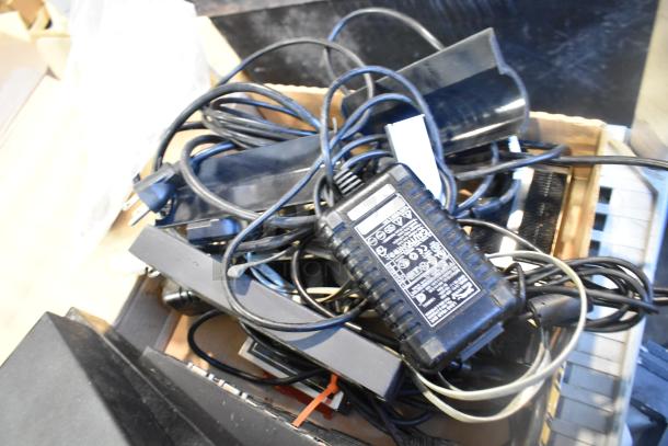 Box of mixed electronics including POS monitor, receipt printers, and wires. Various brands visible on adapters. Condition varies.