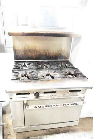 American Range commercial gas 6-burner range with oven, overshelf, backsplash. Visible wear, suitable for restaurant use.