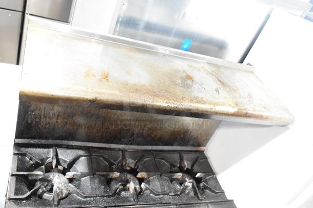 American Range commercial 6-burner gas stove with oven, over shelf, and backsplash, shown with visible wear and grease marks.