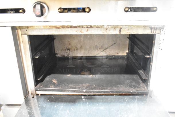 American Range commercial gas-powered range, 6 burners, oven, over shelf, backsplash, visible wear inside oven.