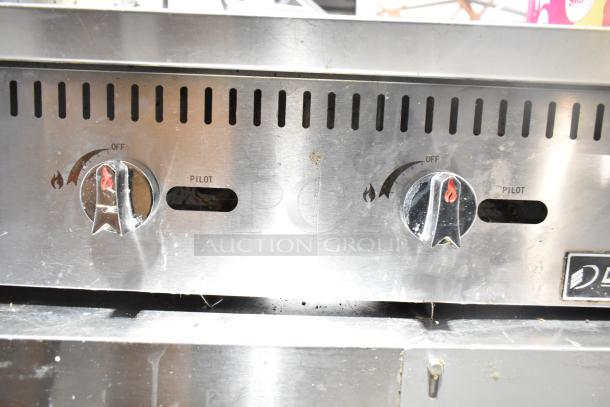 Dukers DCGMA48 griddle, natural gas, 120,000 BTU, dual control knobs, stainless steel, visible wear, pilot markings.