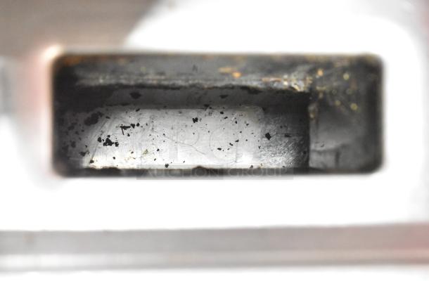 Dukers DCGMA48 griddle burner compartment, showing metal surface with signs of use and grime build-up.