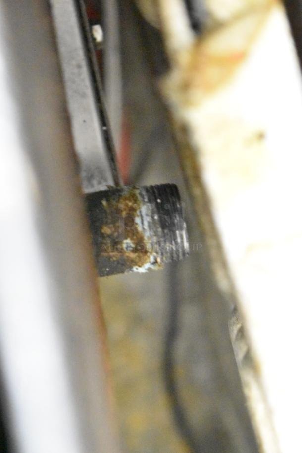 Close-up of a corroded gas pipe connection on a Dukers DCGMA48 commercial countertop griddle, indicating wear.