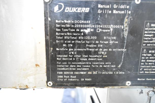 Dukers DCGMA48 Commercial Flat Top Griddle, 120,000 BTU, natural gas, 4 burners, model info and specs on a metal label.