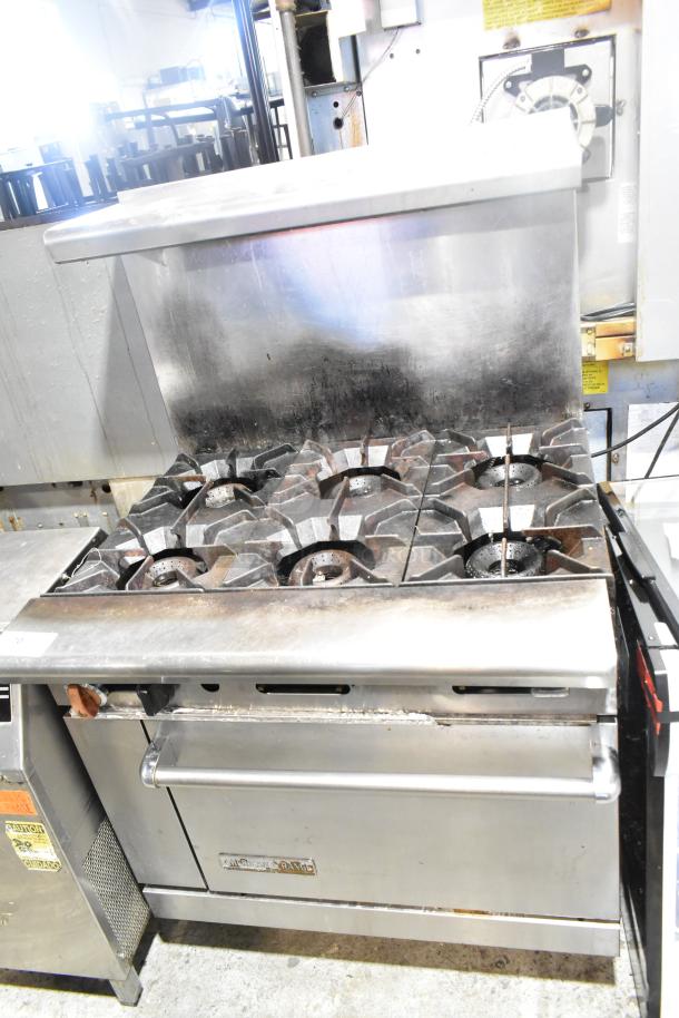American Range commercial 6 burner gas range with oven, overshelf, and backsplash. Used condition, stainless steel exterior.