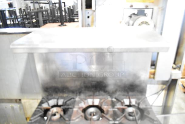 American Range commercial gas-powered 6 burner range with oven, over shelf, and back splash. Used condition.