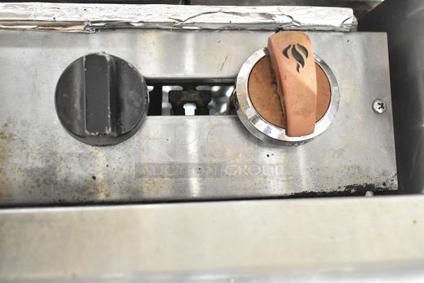 Close-up of control knobs on an American Range commercial gas-powered 6 burner range. Visible wear on metal surface.
