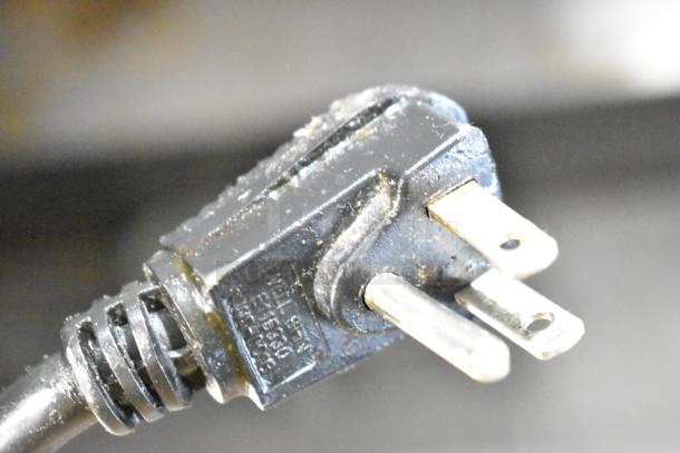 Close-up of a power cord plug for a Continental DL36-15M sandwich salad prep table, showing three prongs and safety markings.