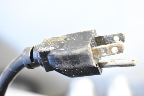 This image shows a close-up of a worn black electrical plug with visible dirt and slight wear on the prongs.