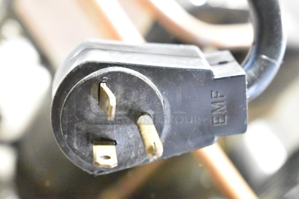 Close-up of a power plug with "EMF" markings, associated with a Traulsen RLT232WUT-FHS commercial freezer.