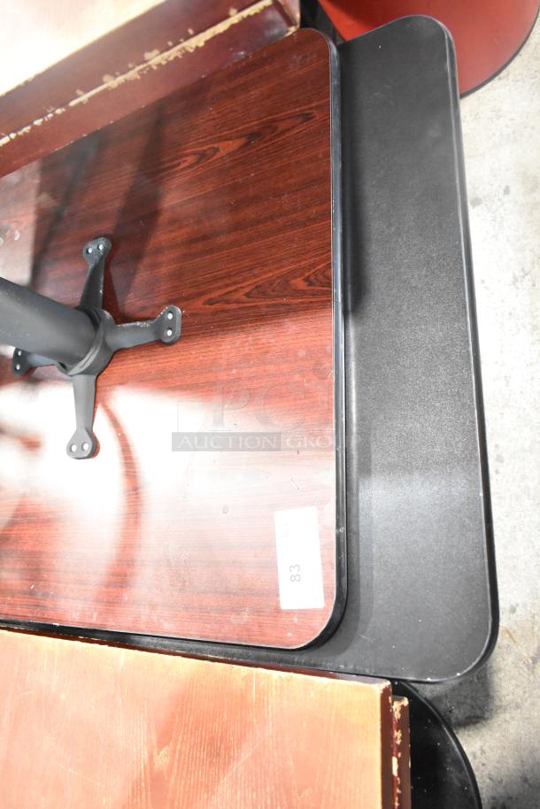 Two dining height tables with black tabletops and metal bases, rectangular shape. Visible label shows "83". Good condition.