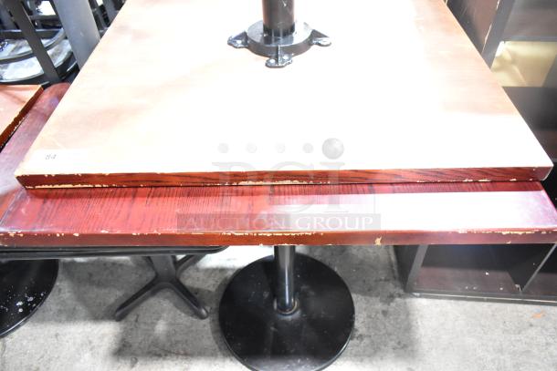 Two bar height tables with wood pattern tabletops and metal bases. Visible wear on edges. Tag marked "84".