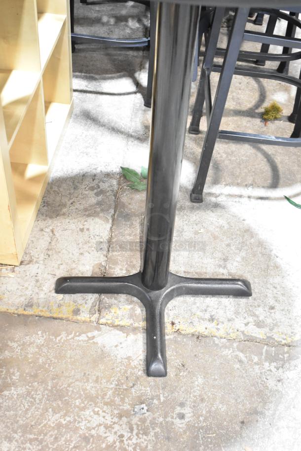 Two bar-height tables with black tabletops and sturdy metal bases. Ideal for commercial or home use. Visible minor wear.