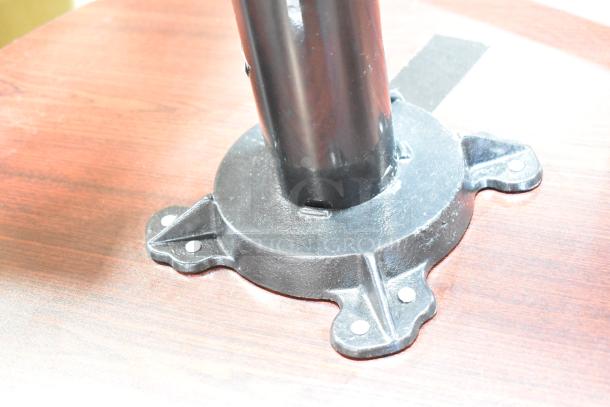 Bar height table with black tabletop and sturdy metal base, shown in close-up, highlighting base design and condition.