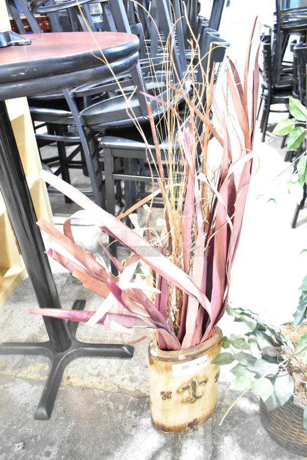 Two artificial plants in decorative pots; one with tall, purple leaves and one with green leaves. Includes auction label.