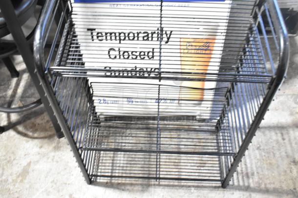 Black wire shelving unit with multiple tiers, sturdy design. Includes a visible "Temporarily Closed Sundays" sign.