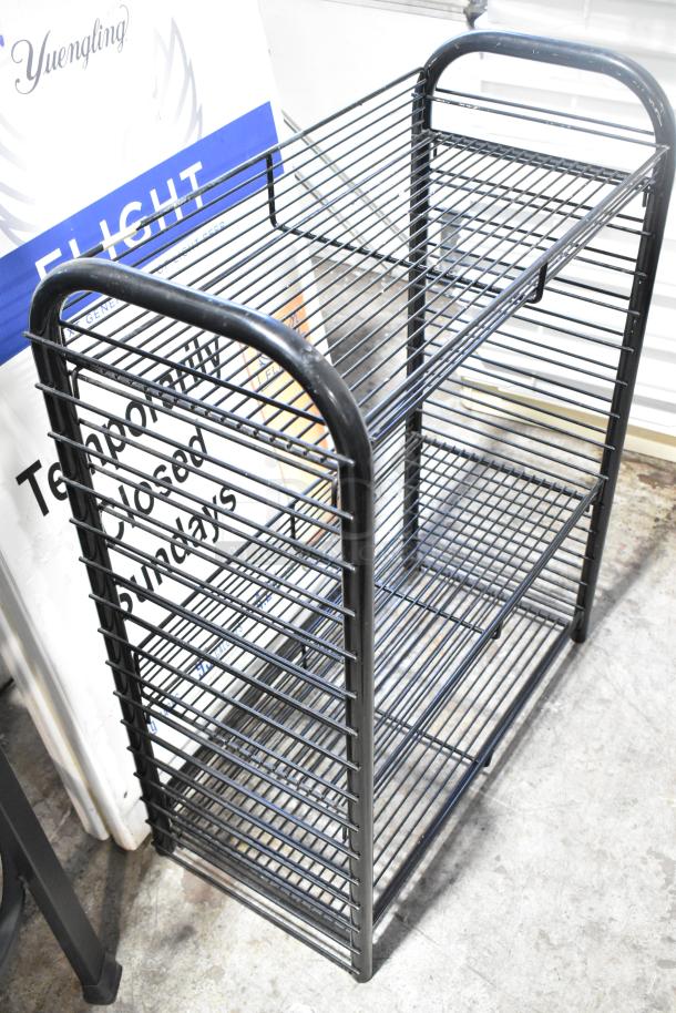 Black wire shelving unit with three tiers alongside a white A-frame sidewalk sign, in good condition.