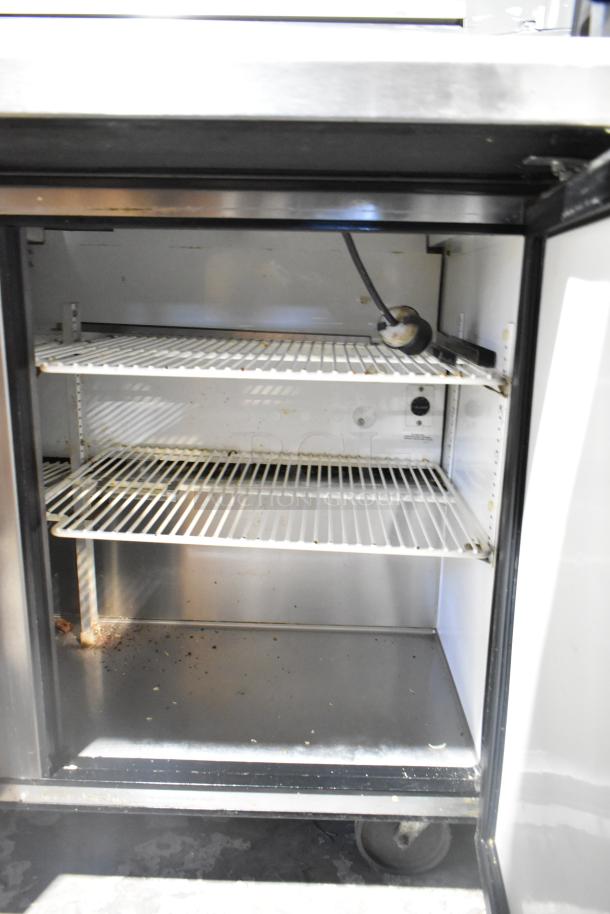 True TSSU-72-30M-B-ST commercial prep table interior with wire shelves and visible wiring. Condition shows signs of use.