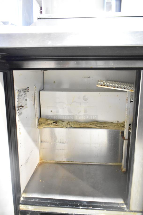 True TSSU-72-30M-B-ST prep table interior showing metal shelves and manufacturer label. Note signs of wear.