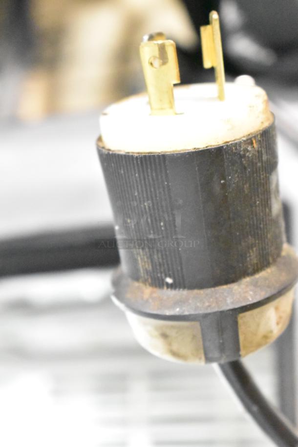 Close-up of an electrical plug from the True TSSU-72-30M-B-ST prep table, featuring a three-prong design. The plug shows signs of wear.