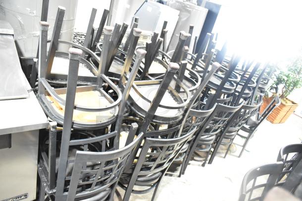 Set of 36 black window-back dining chairs with black seat cushions, stacked, showing sturdy construction and sleek design.