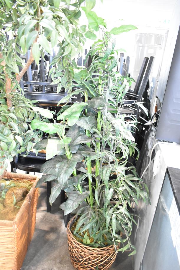 Two artificial plants in woven baskets, tall and leafy, ideal for indoor decoration. Good condition, vibrant green foliage.