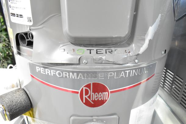 Rheem RSB565E Hot Water Heater featuring Performance Platinum series with visible dents and scratches on gray exterior.