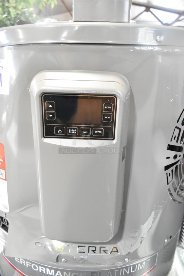 Rheem RSB565E Hot Water Heater, gray, digital control panel, "ProTerra" label, minor surface scratches visible.
