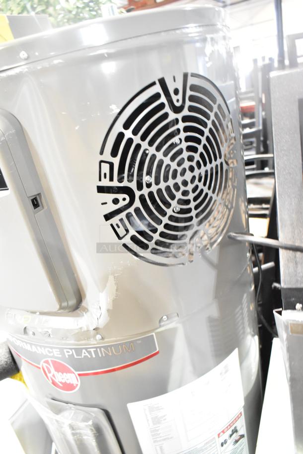Rheem RSB565E Hot Water Heater, Performance Platinum model, gray finish, visible labels, slight surface wear.